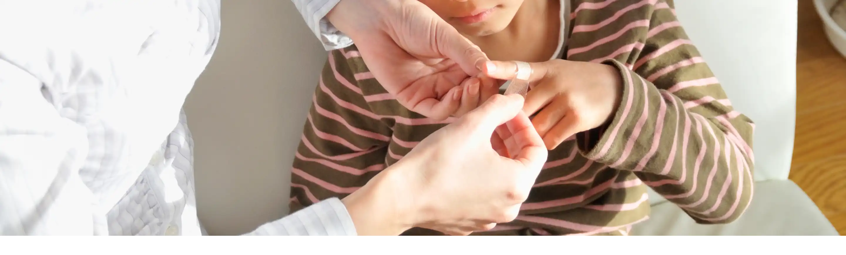 An adult providing first aid care to a child's finger at home.