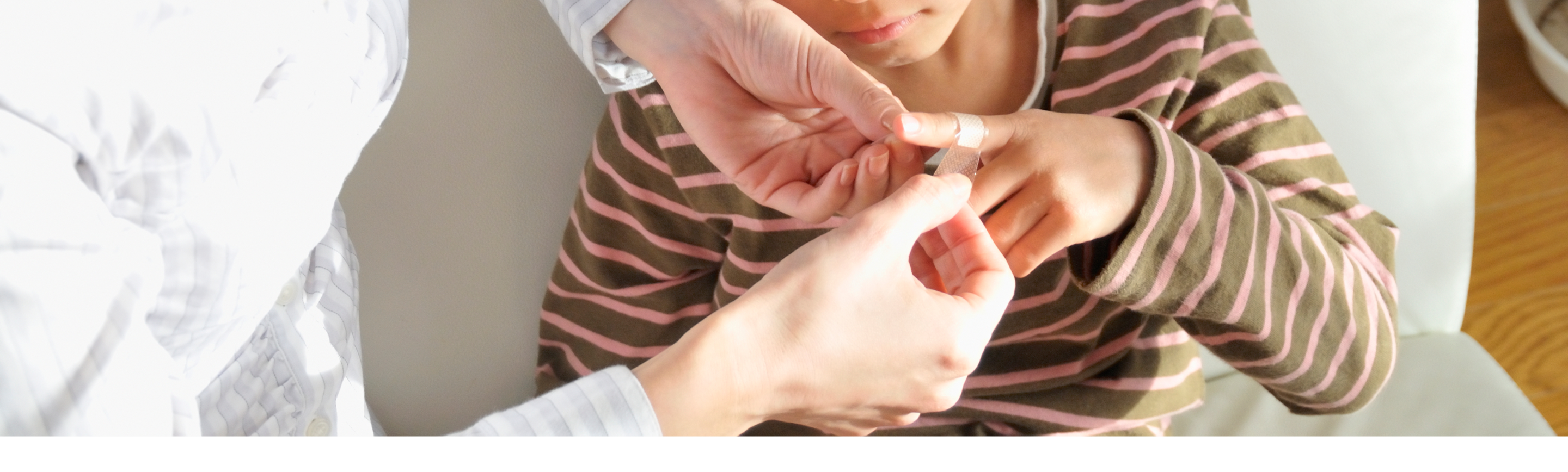 An adult providing first aid care to a child's finger at home.