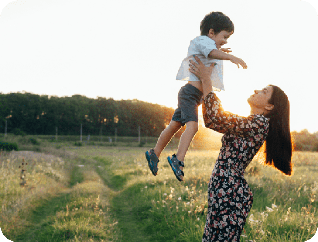 Woman in dress holding boy in field