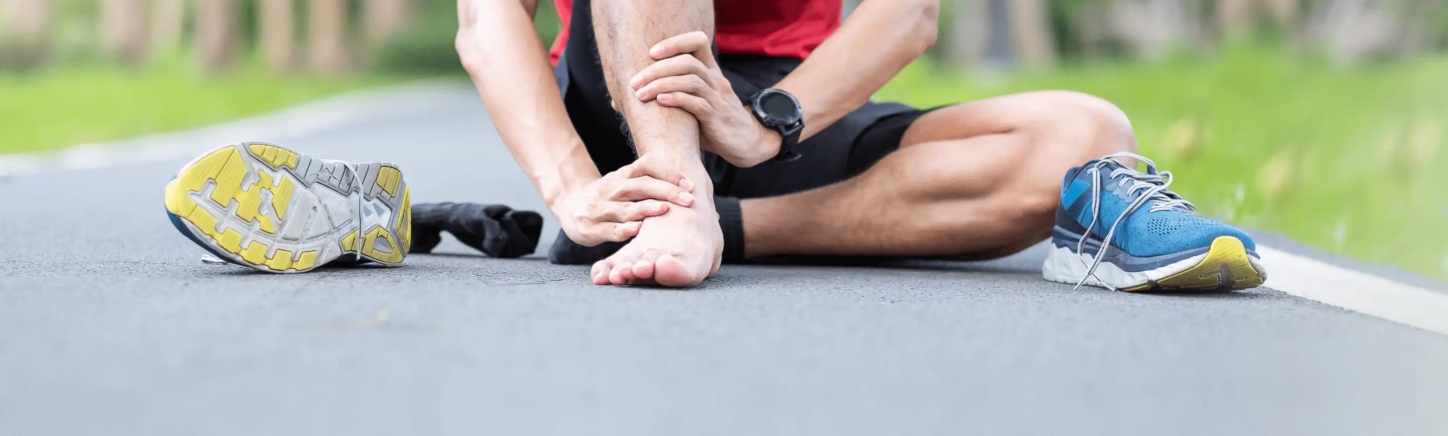 Man sitting on pavement to care for blisters caused by running sneakers