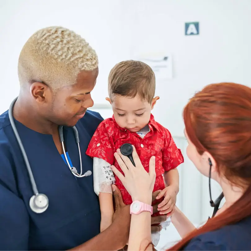 Two doctors checking the heart rate of a young child.