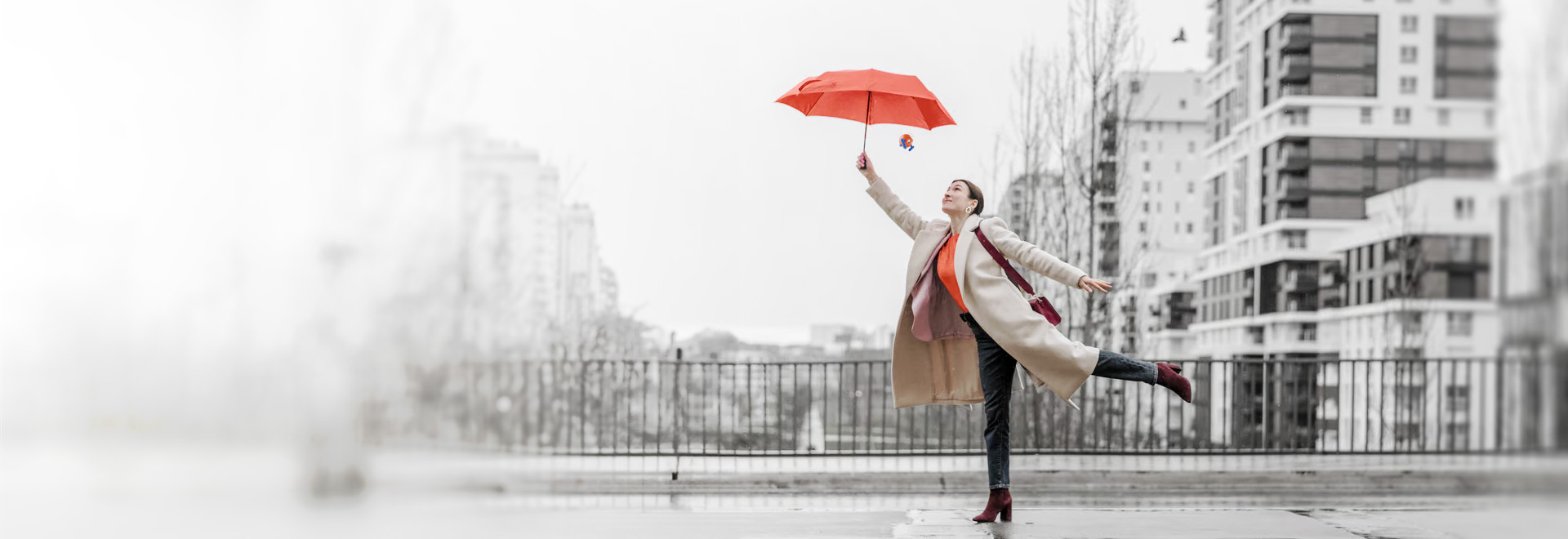 woman standing with one leg outstretched holding an orange umbrella