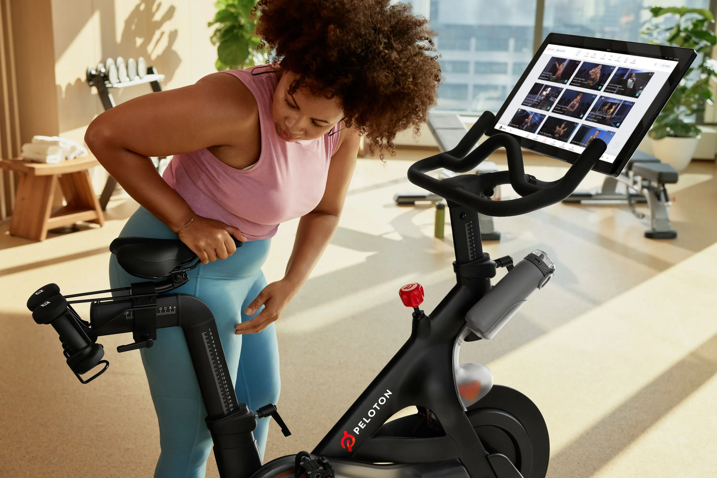 Exerciser adjusting the Peloton seat prior to a workout