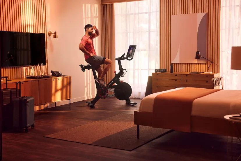 A man using the peloton bike in his hotel room
