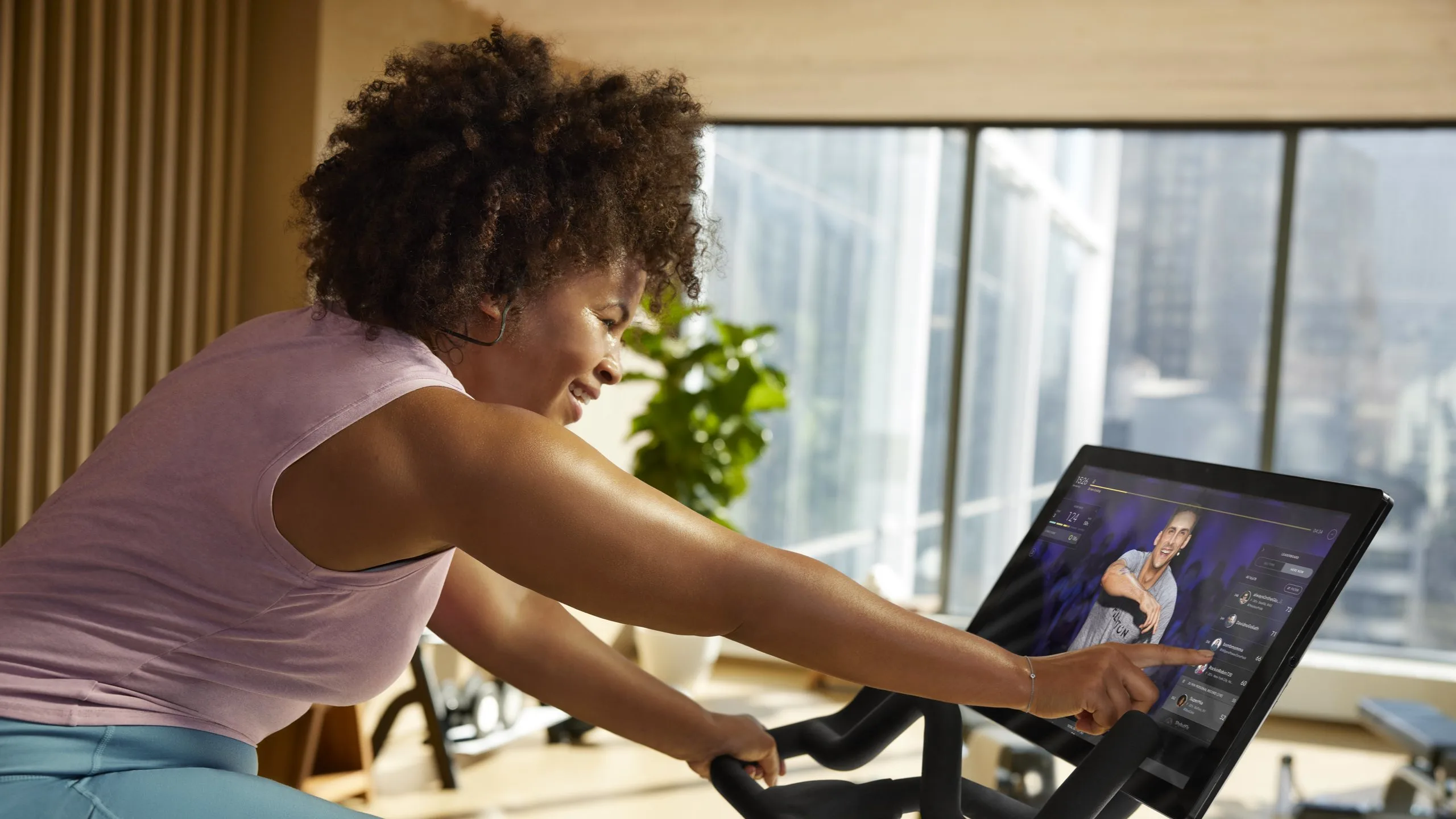 Exerciser interacting with a console on a Peloton Bike