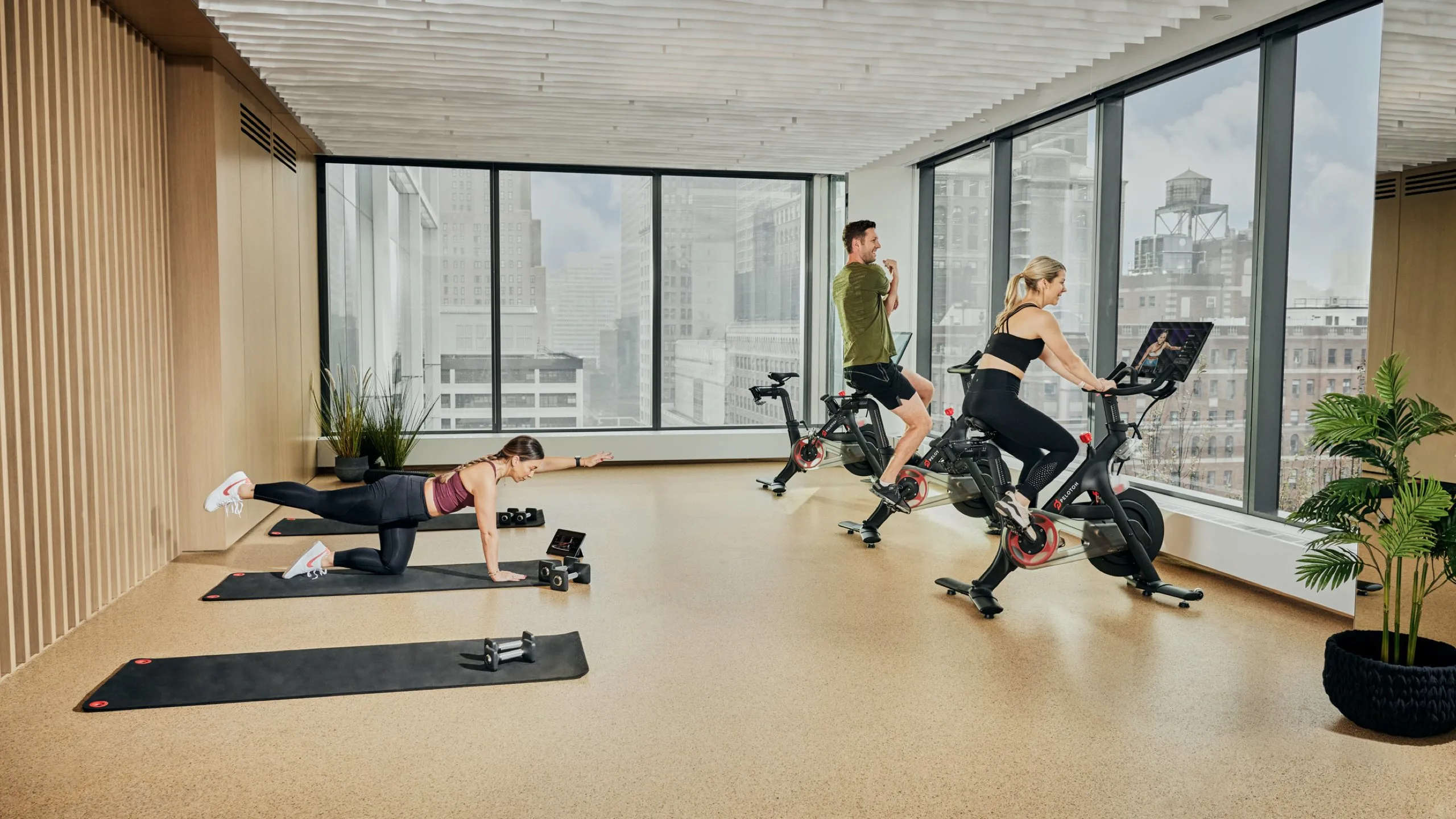 Exercisers using Peloton stationary bikes in a gym