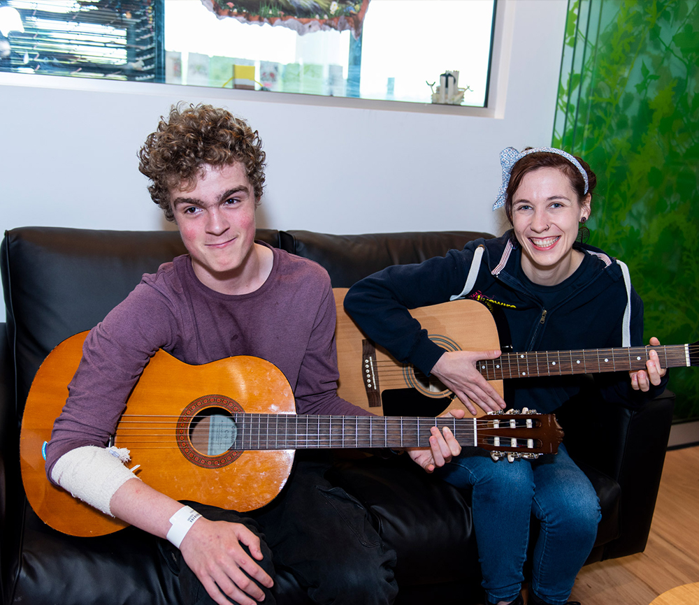 Teen playing guitar with Livewire facilitator