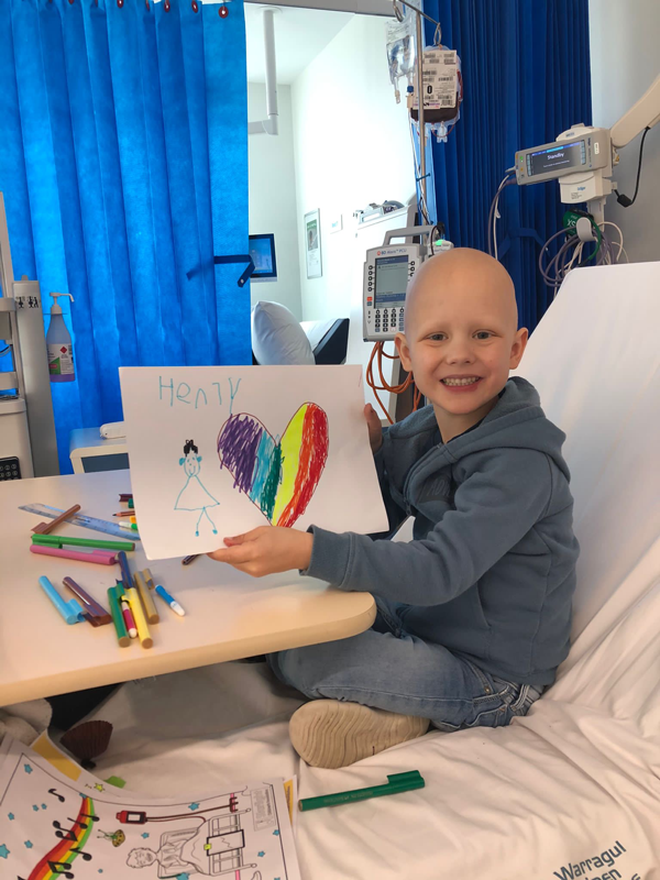Henry in hospital bed with name sign