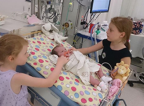 Baby Holly with her sisters in hospital