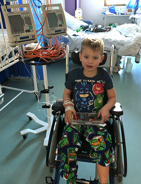 Oliver in hospital sitting in wheelchair