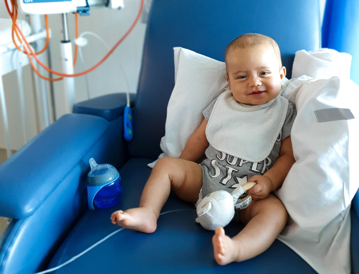 Mason smiling in blue hospital chair 720 x 550