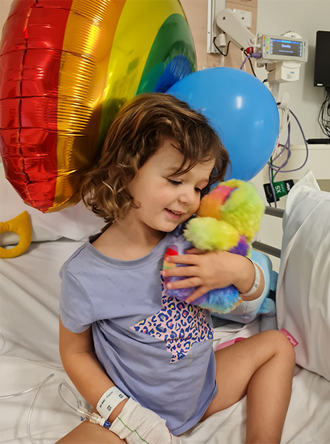 Chloe in hospital bed with balloons