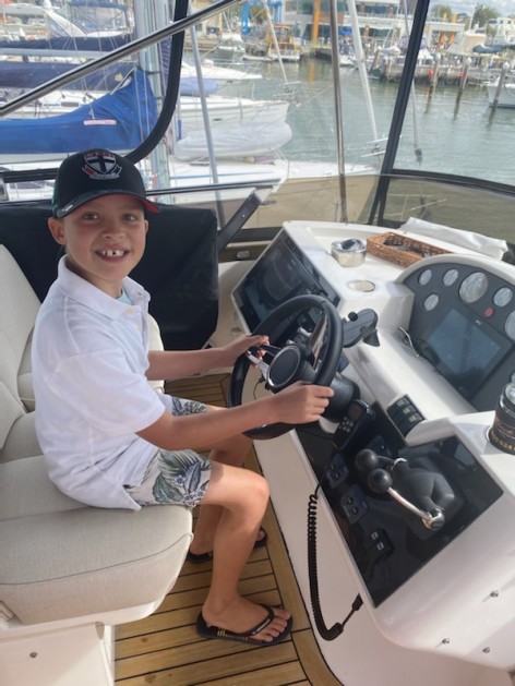 Tommy at the steering wheel of a boat