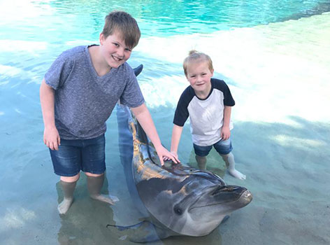Will and brother patting dolphin