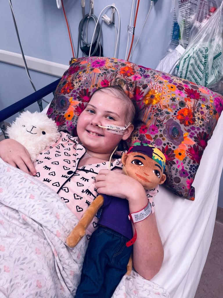 Emma with toys in hospital bed