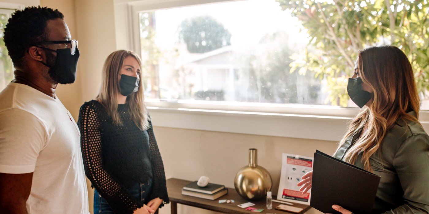 Two people tour a new home in masks