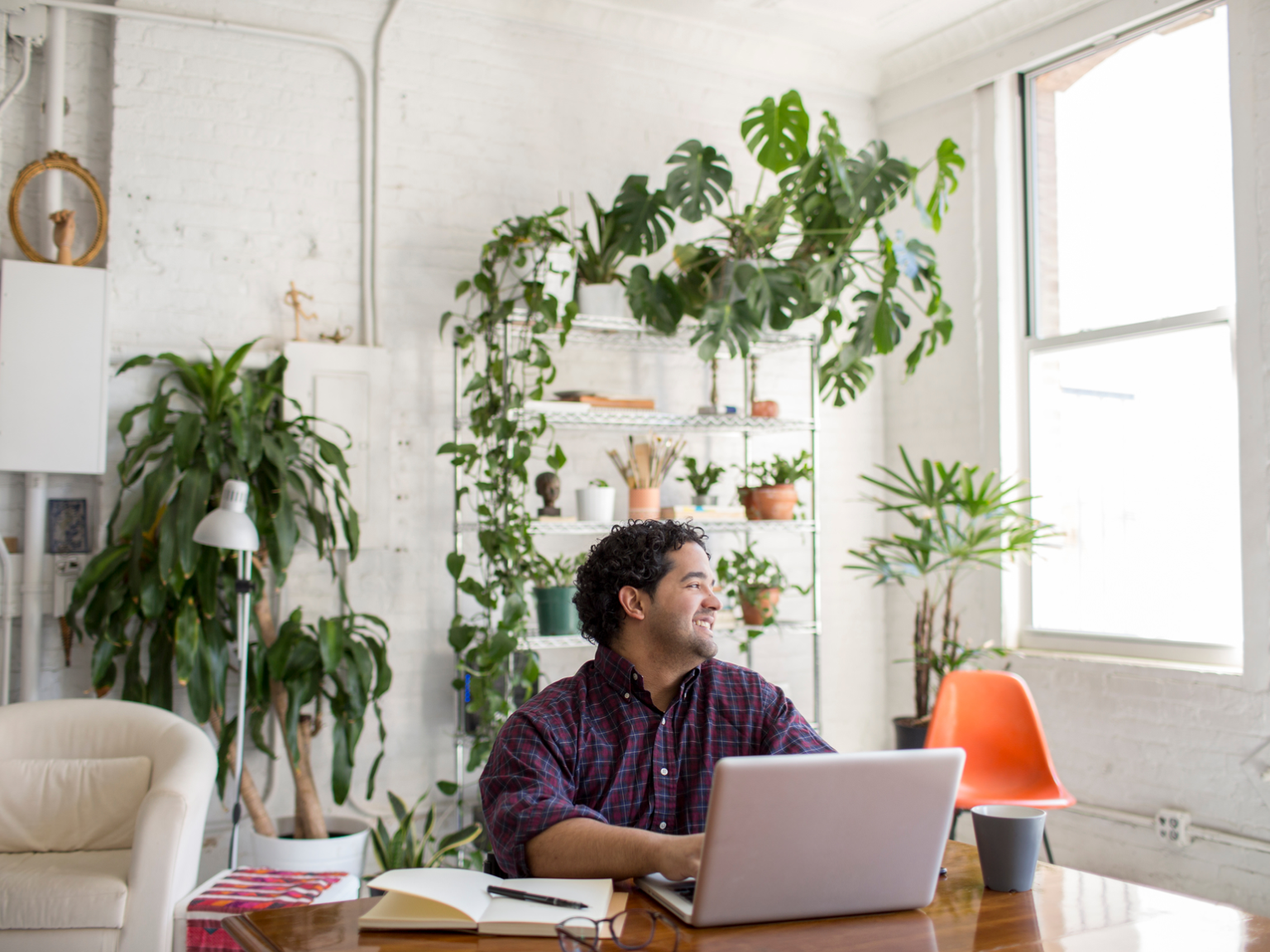 Image of renter working at the table in apartment with plants along the wall