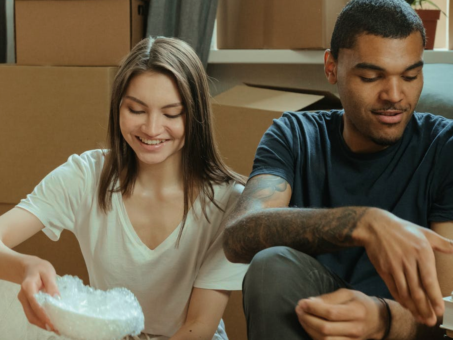 Image of two renters in their new living room with moving boxes in the background
