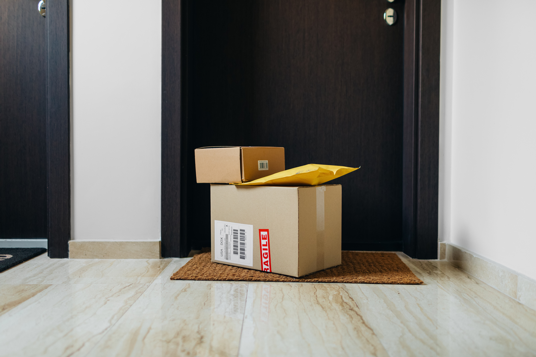 An image of three packages in front of an apartment door