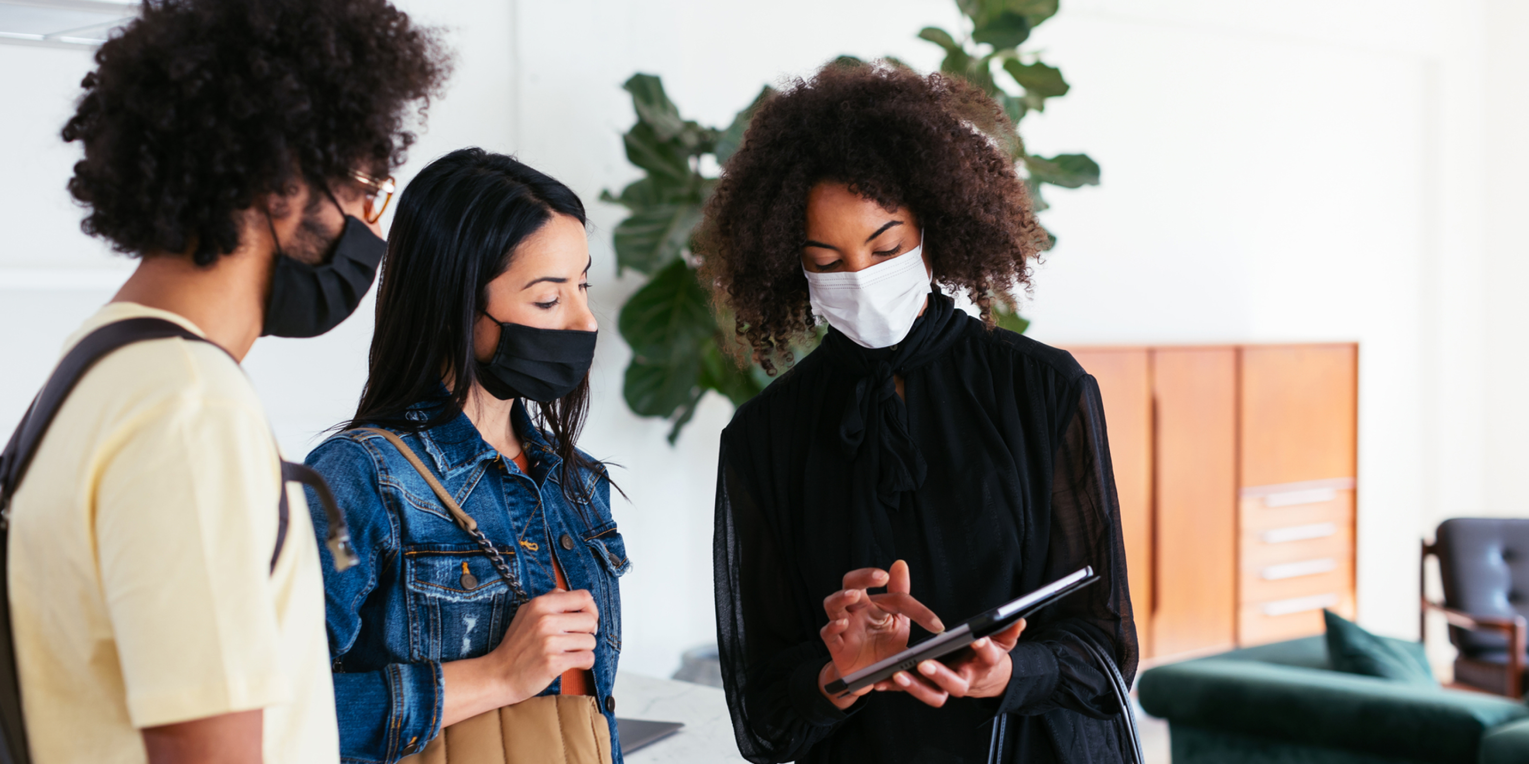 A image of a leasing agent wearing a mask and showing her future renters how to sign up for Rhino on an ipad. 