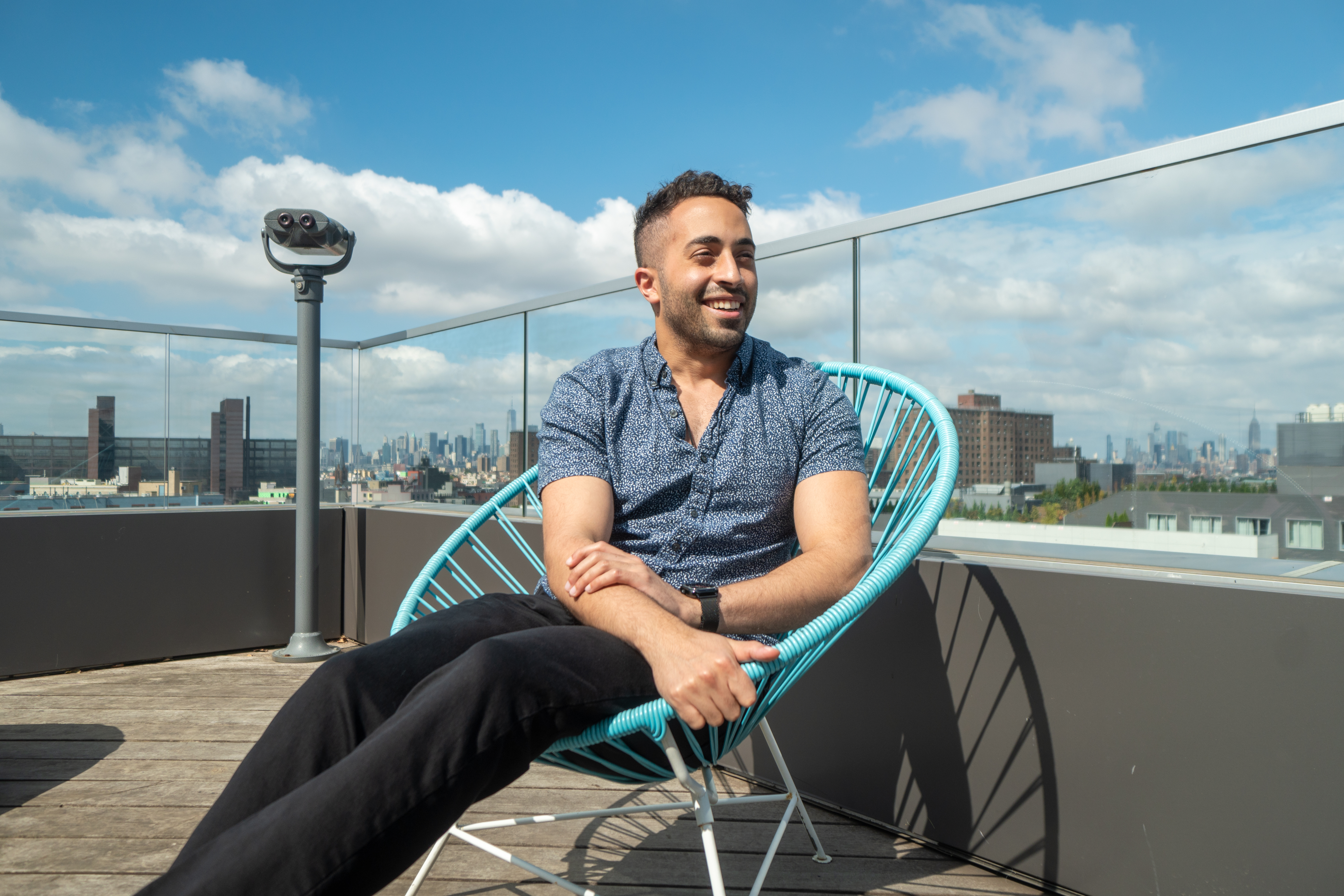 A photo of Ismail smiling now that he lives at the Denizen while enjoying the rooftop