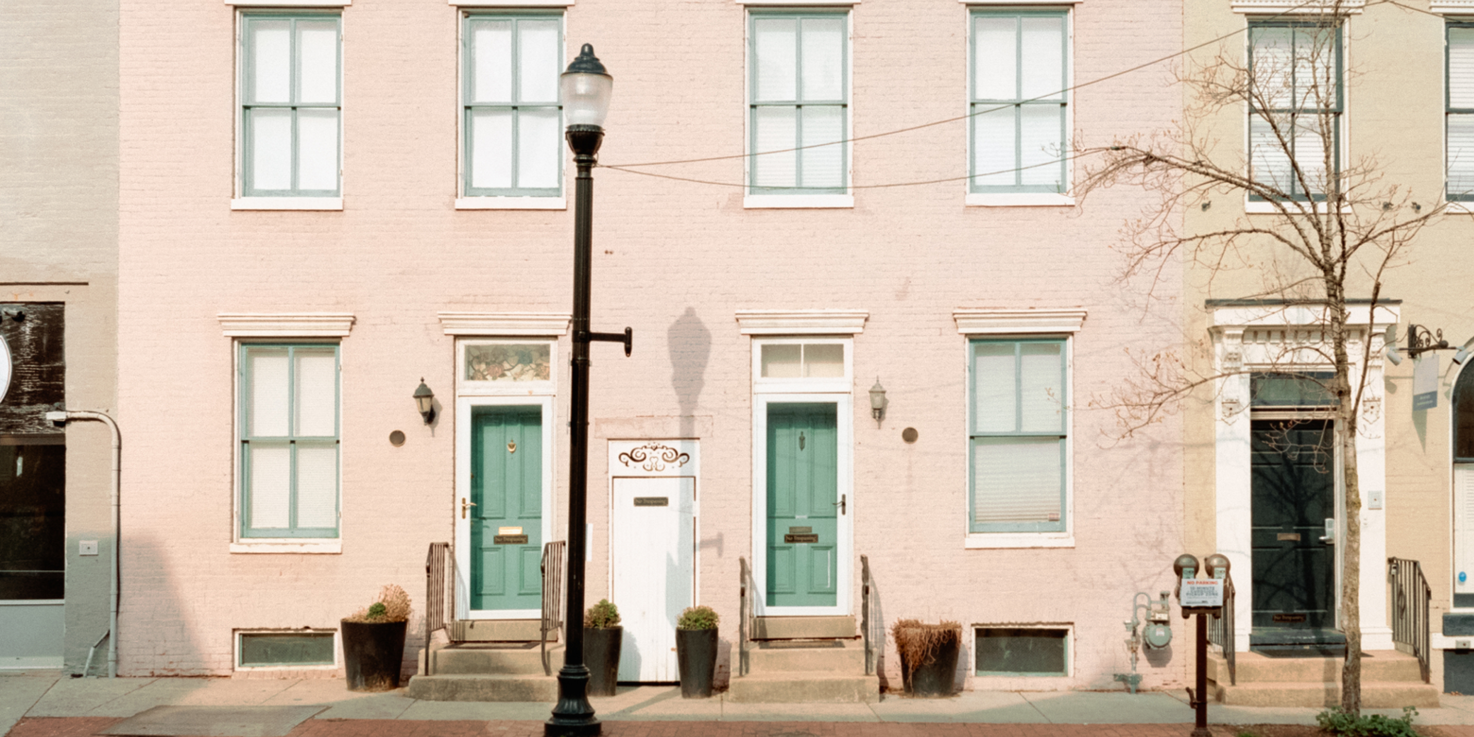 Un'immagine di un condominio duplex rosa con un'adorabile porta verde