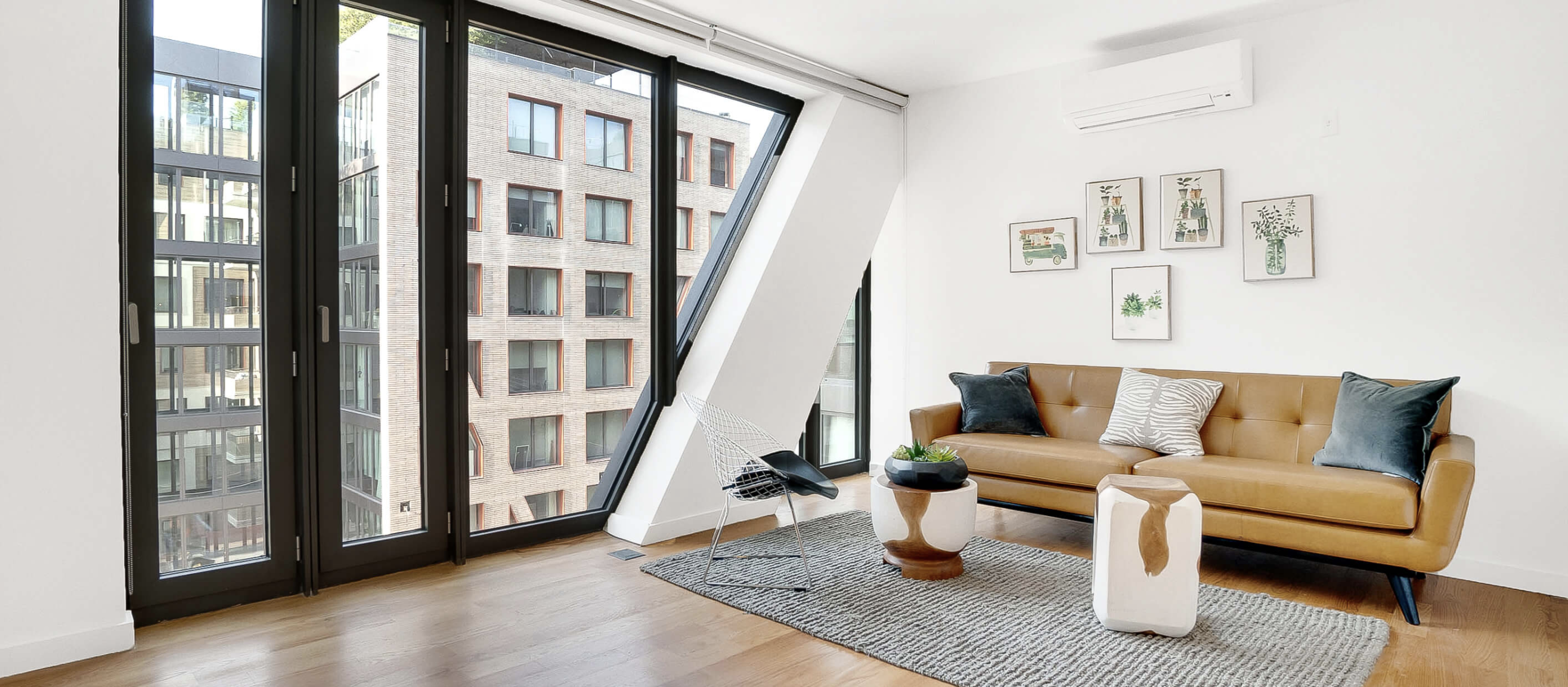 A photo of a living room of an apartment at the Denizen. It is clean, modern and with hardwood floors 