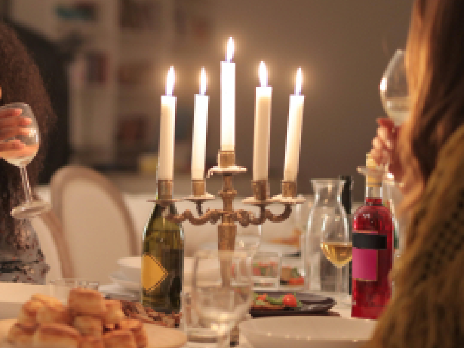Image of renters around candles at a dinner table. 