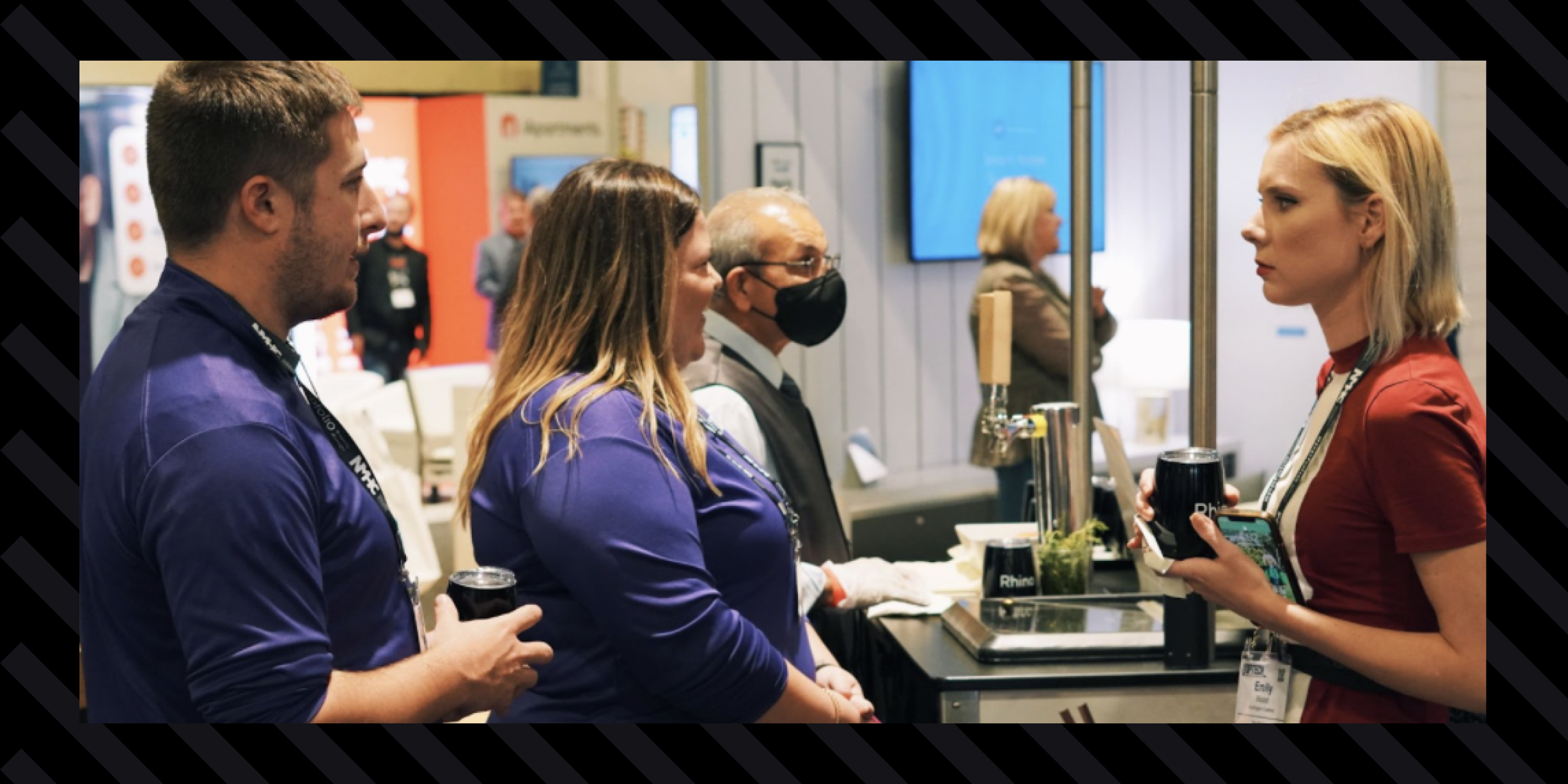 An image of Rachel Allen and Michael Brevdah chatting with a booth visitor and splitting a cocktail at Optech 2021 