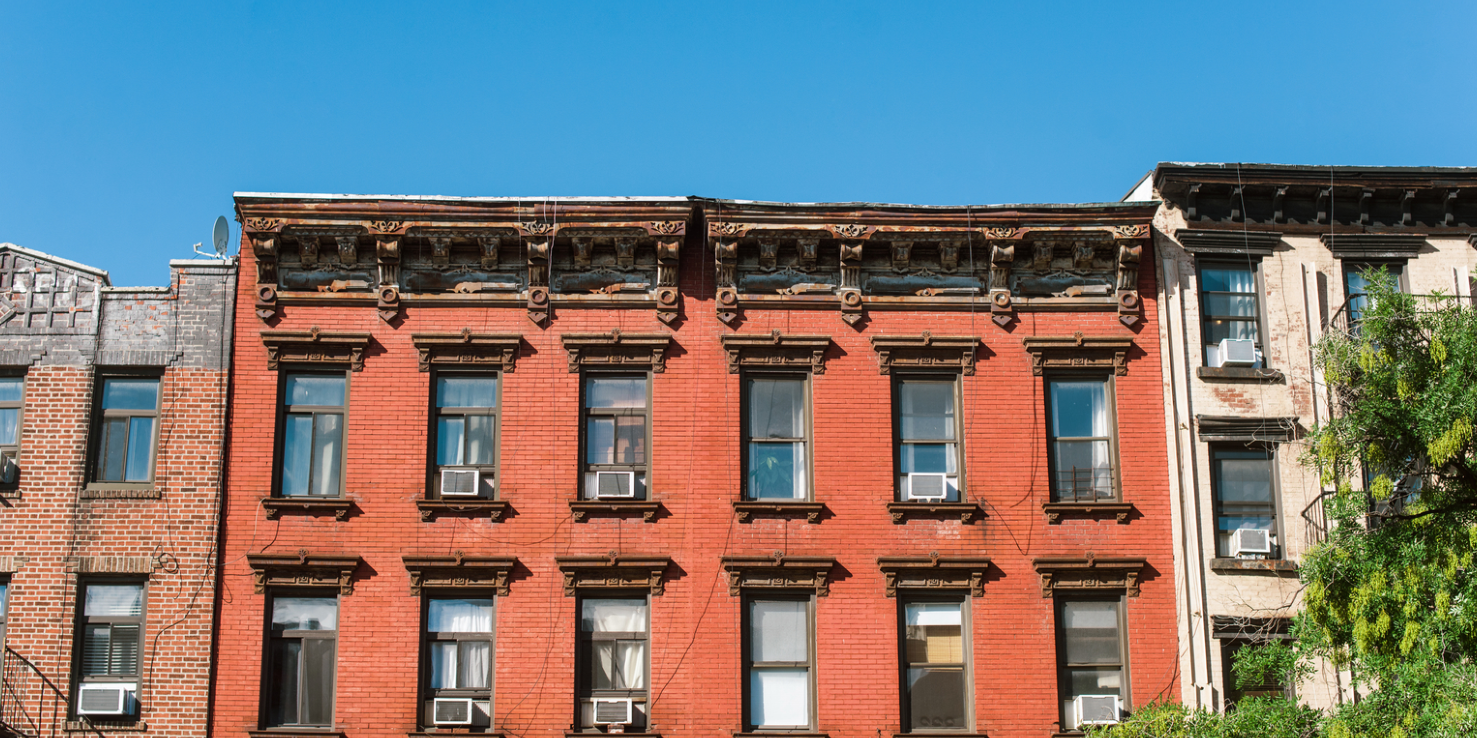 An image of a red brick apartment building and a blue sky in New York City 