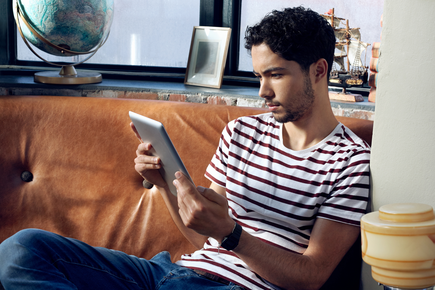 An image of a renter sitting on his couch and using an ipad on free WiFi