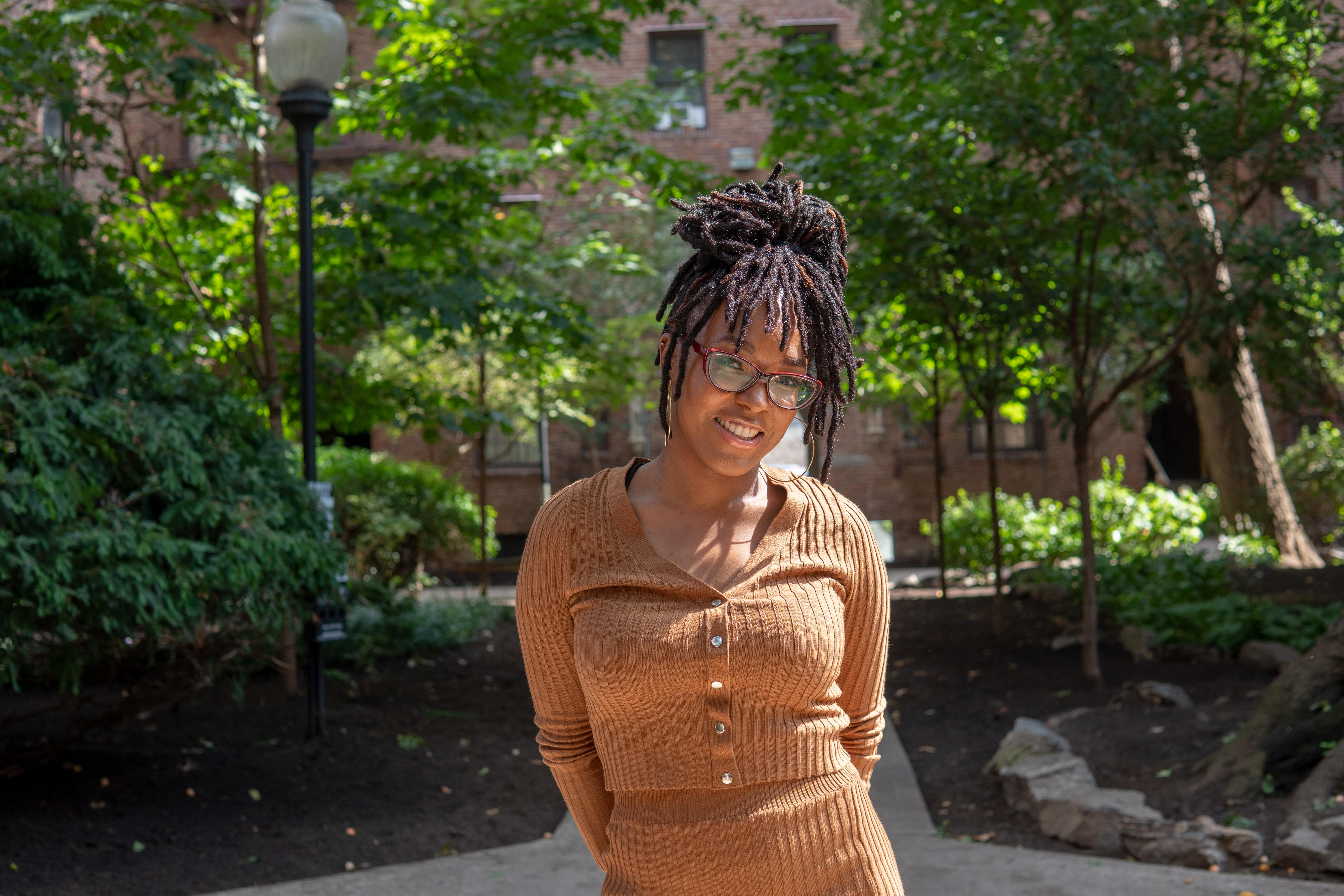 an image of LaToya Lennard with glasses on and smiling in the garden of her apartment complex 