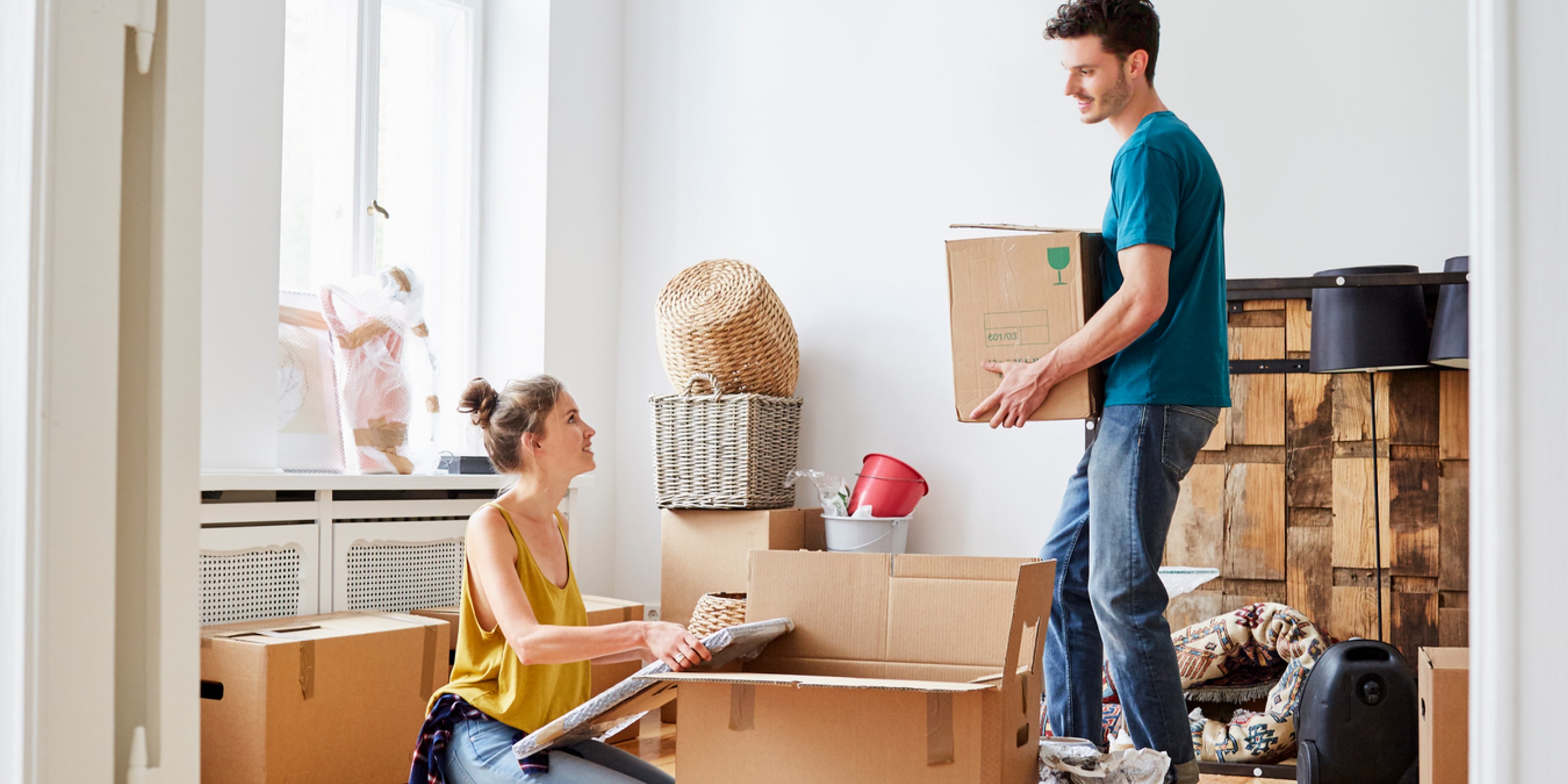 An image of two renters moving into a brand new apartment with their boxes. They are smiling at one another 