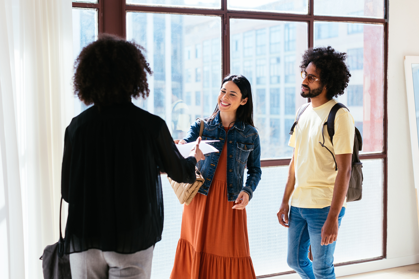 An image of a landlord handing two happy renters a lease for their consideration 