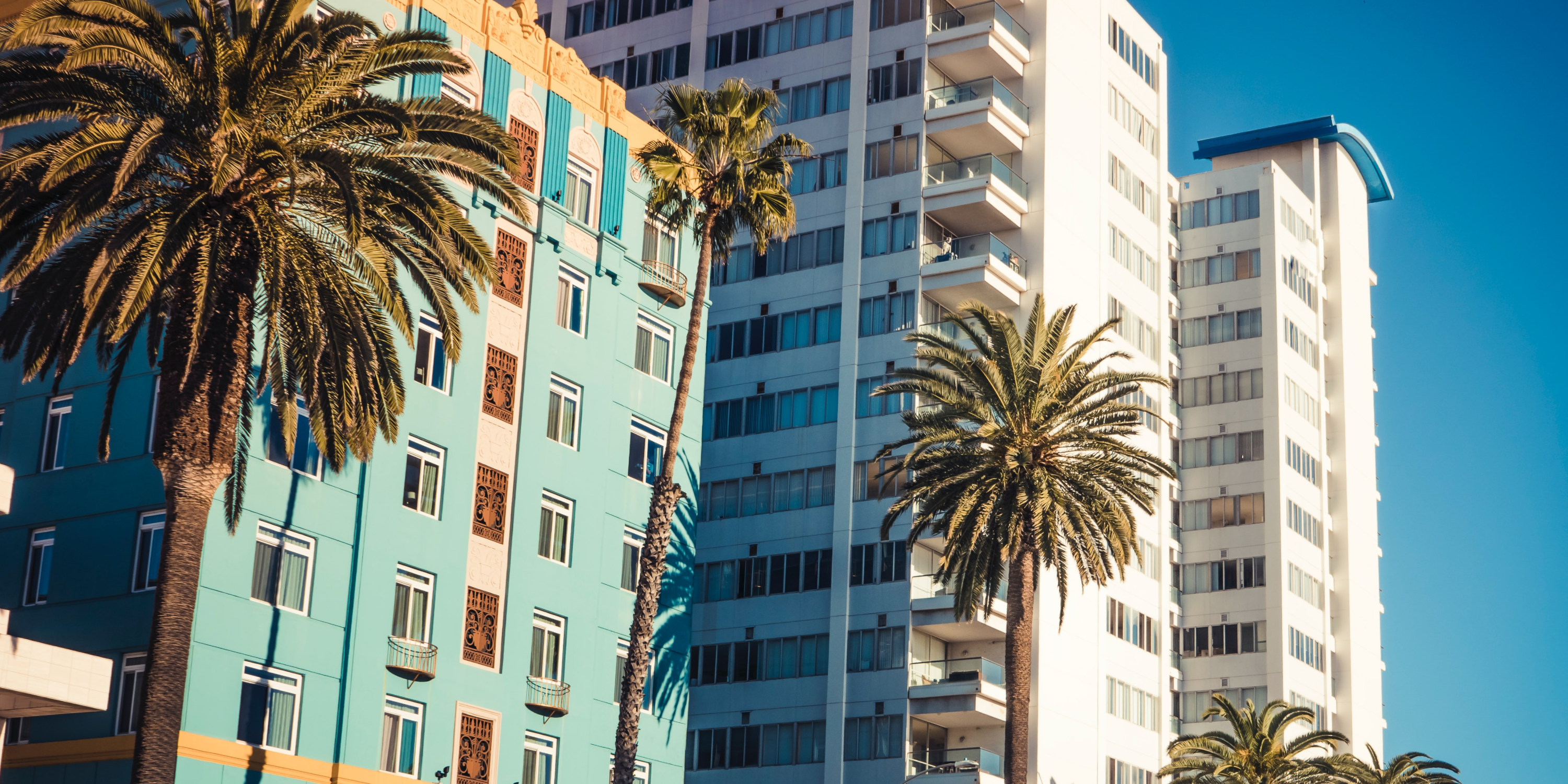 An image of a blue and white apartment building and palm trees in California