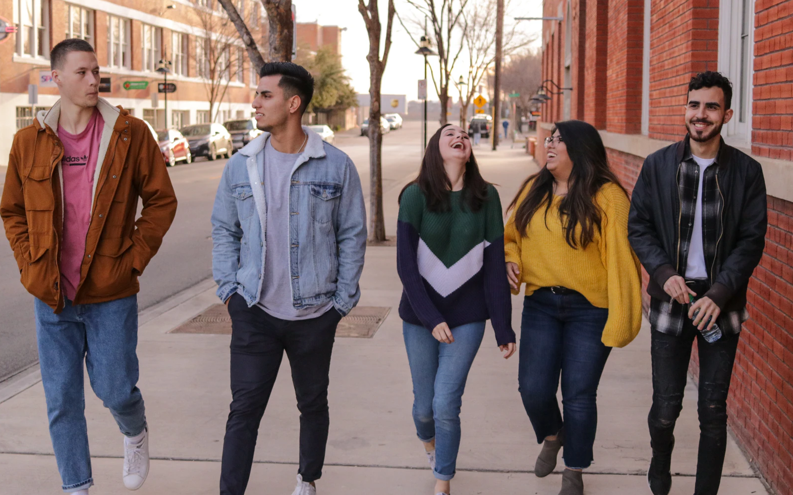 Image of a group of college renters walking down a street and outside apartments