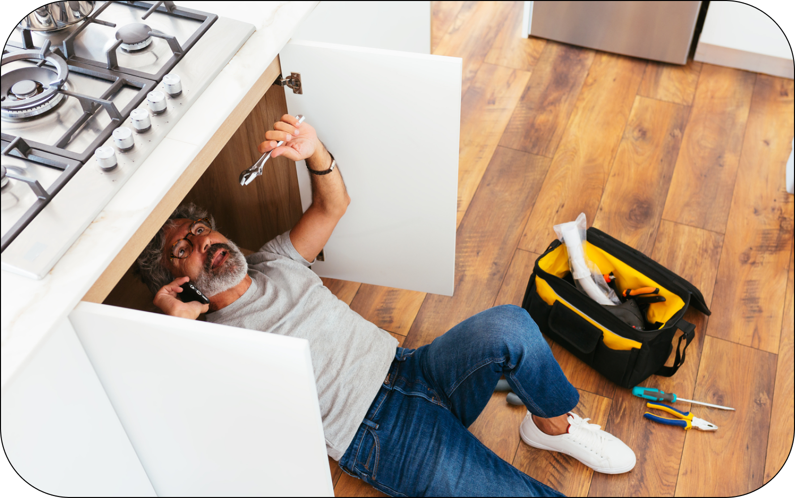 Image of a property manager doing maintenance on the sink in their rental property kitchen. 