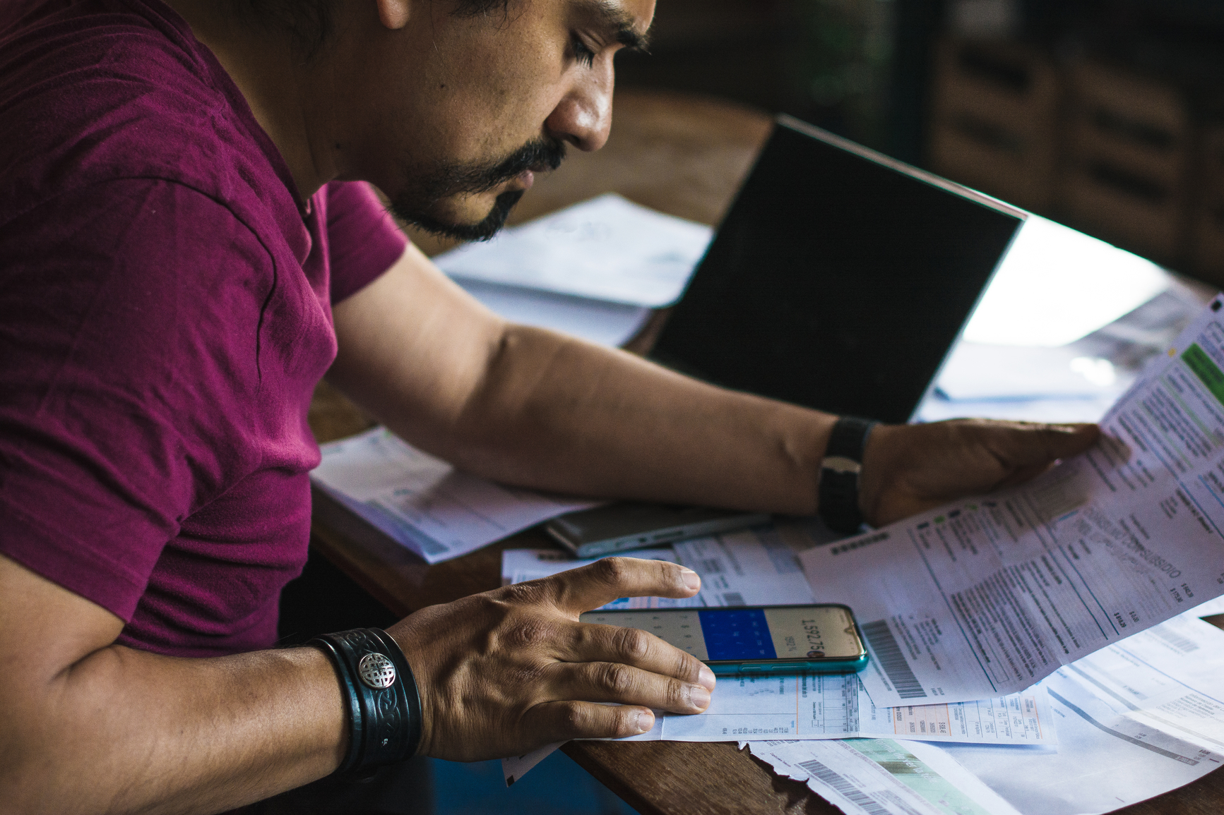 An image of a man in a purple shirt doing taxes for his rental property and crunching numbers on a calculator 