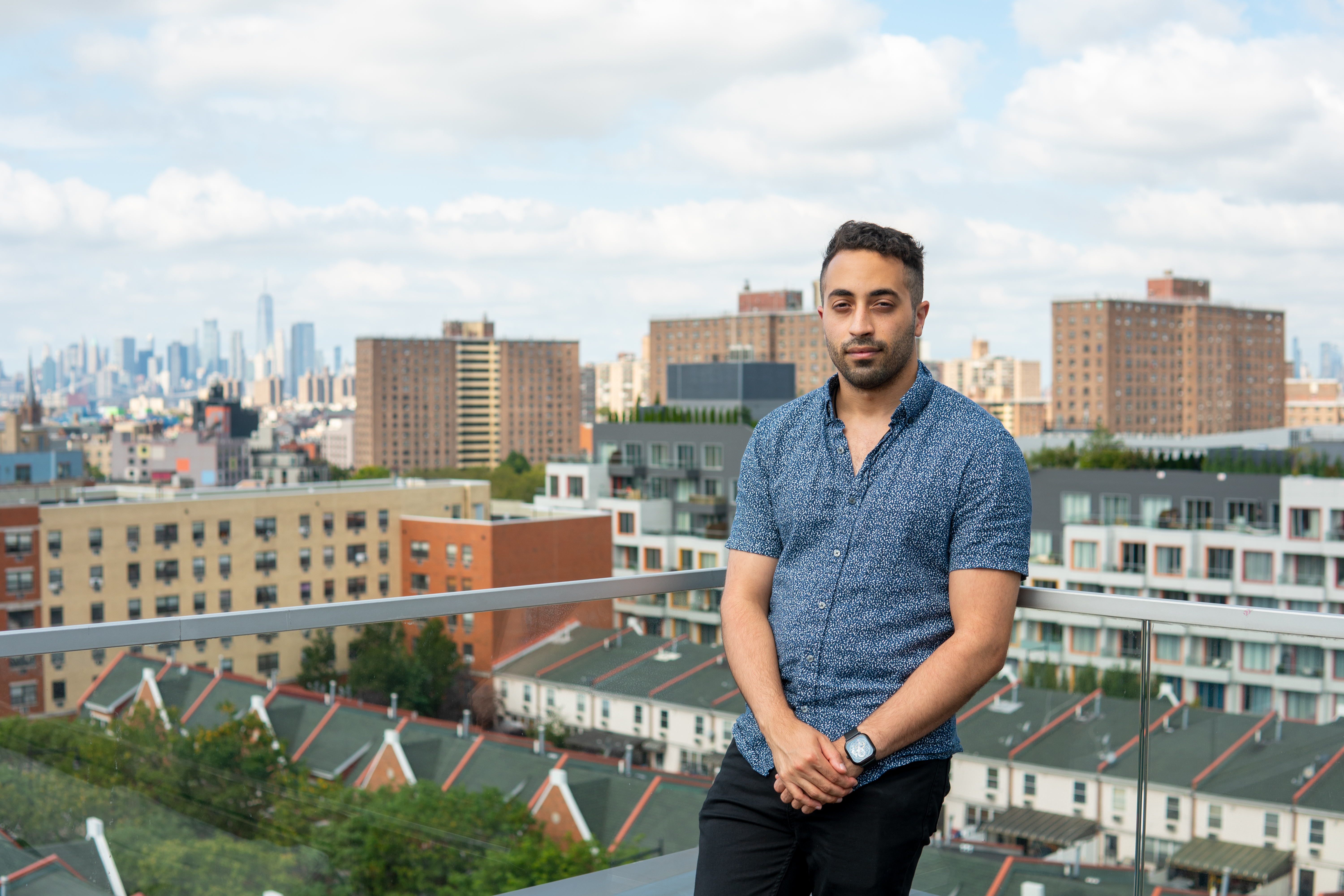A photo of Rhino renter Ismail Kheir on the rooftop of The Denizen in Bushwick, an apartment complex. Manhattan is visible behind him in on the horizon 