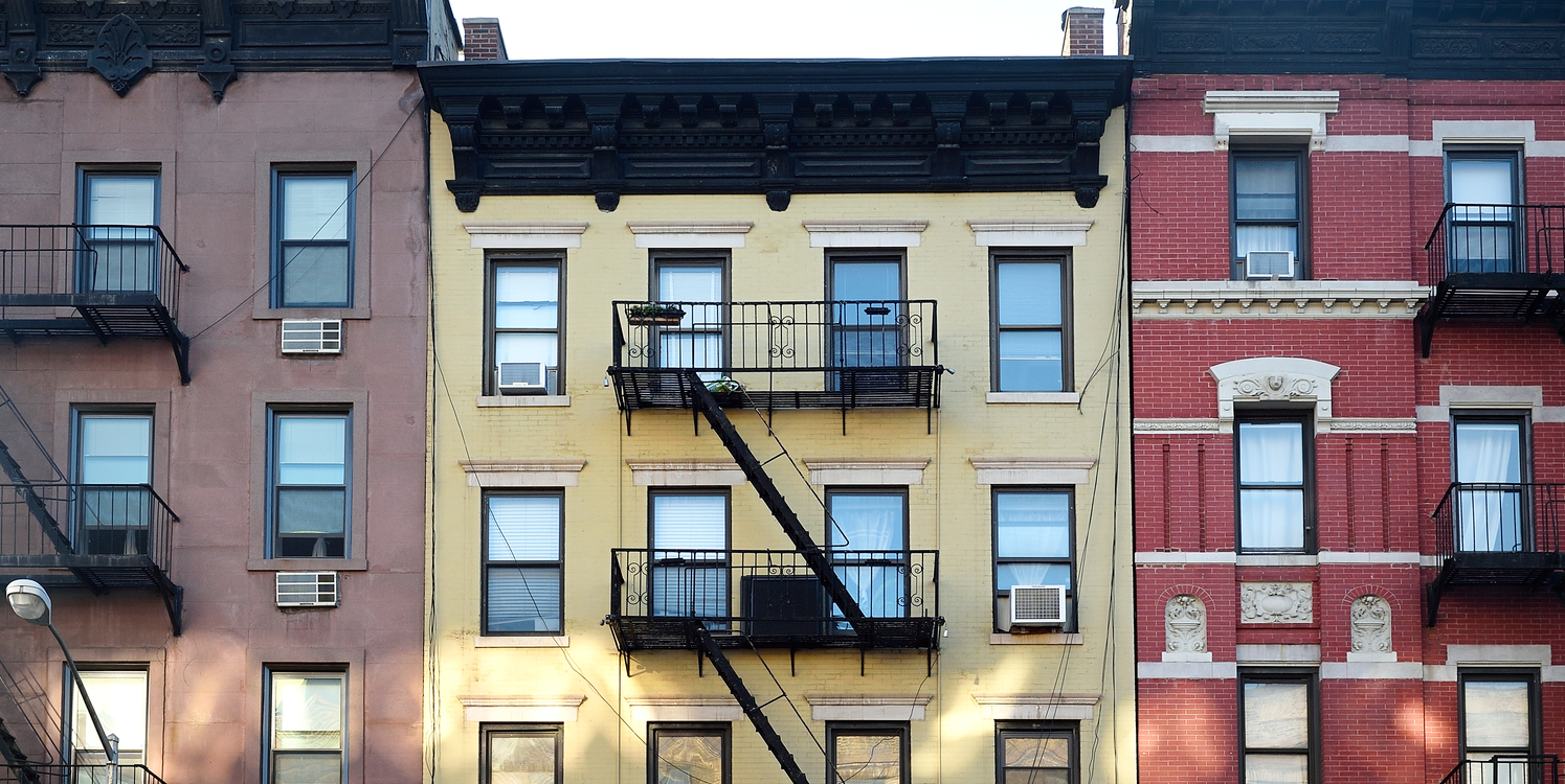 An image of three apartment buildings with fire escapes in New York City 