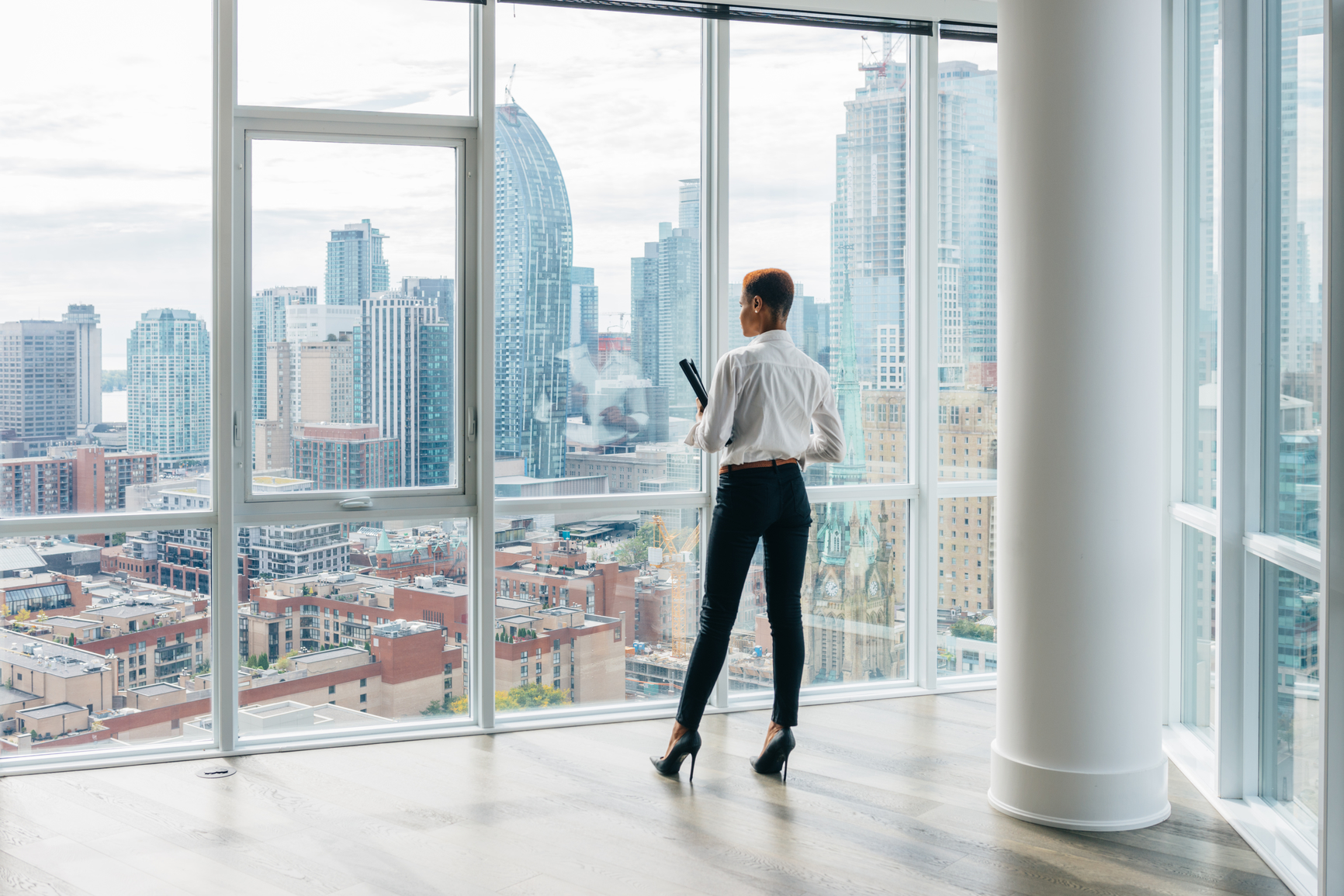 An image of a real estate agent in a high rise building, looking out at the cityscape 