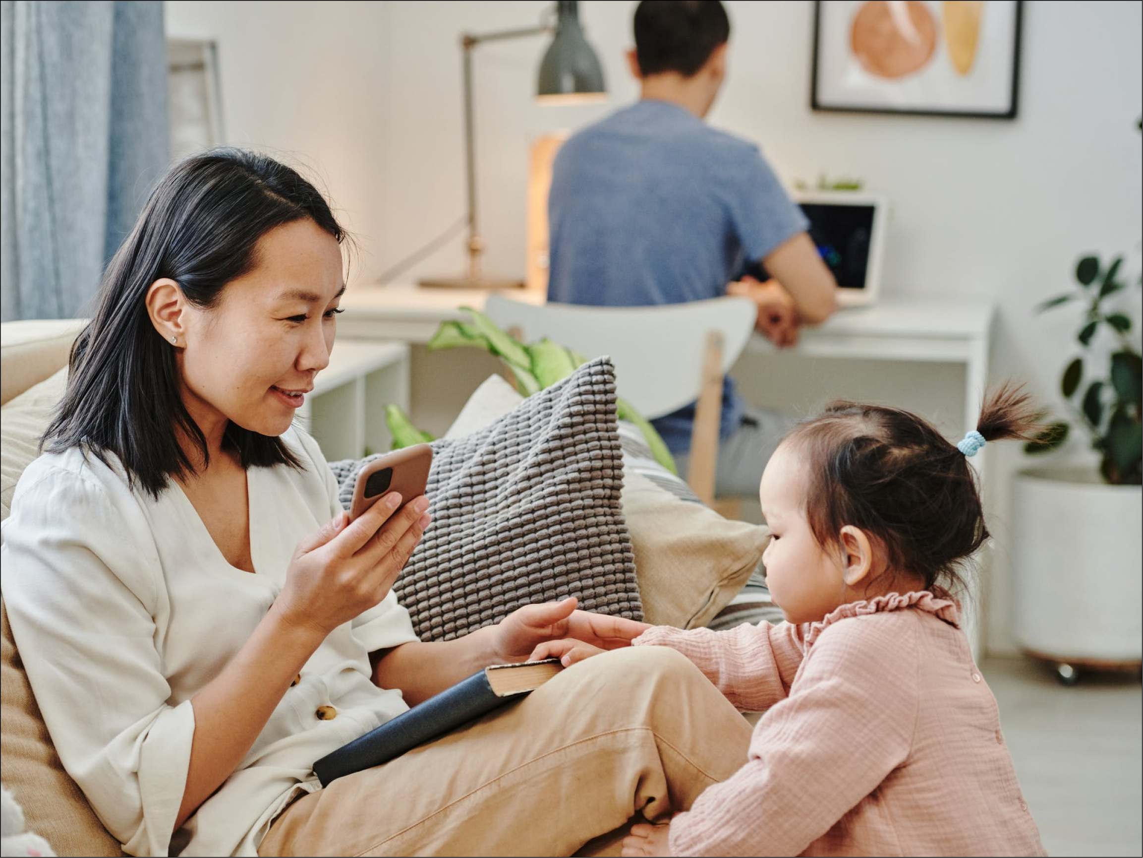 Image of renters and their child sitting in the bright living room, working and playing