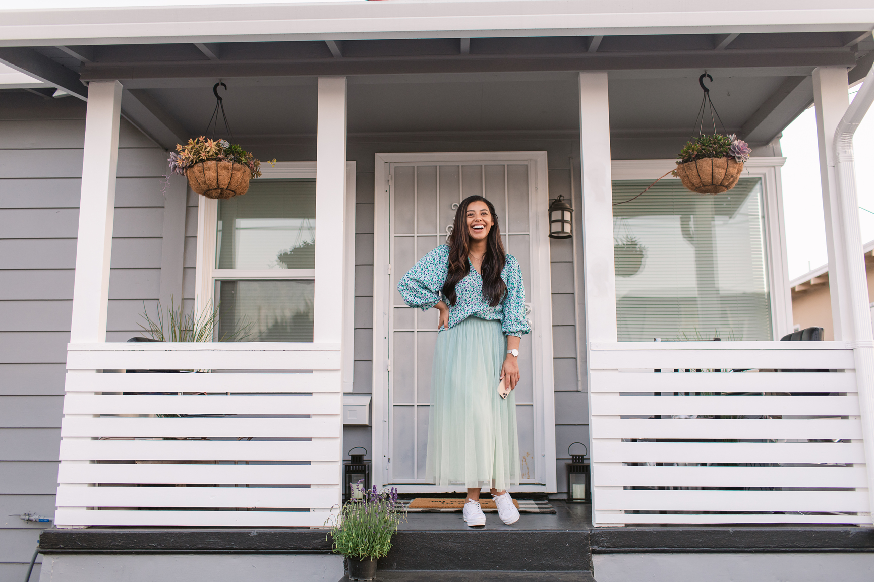 A woman on the porch of her new single-family home rental. She is smiling. 