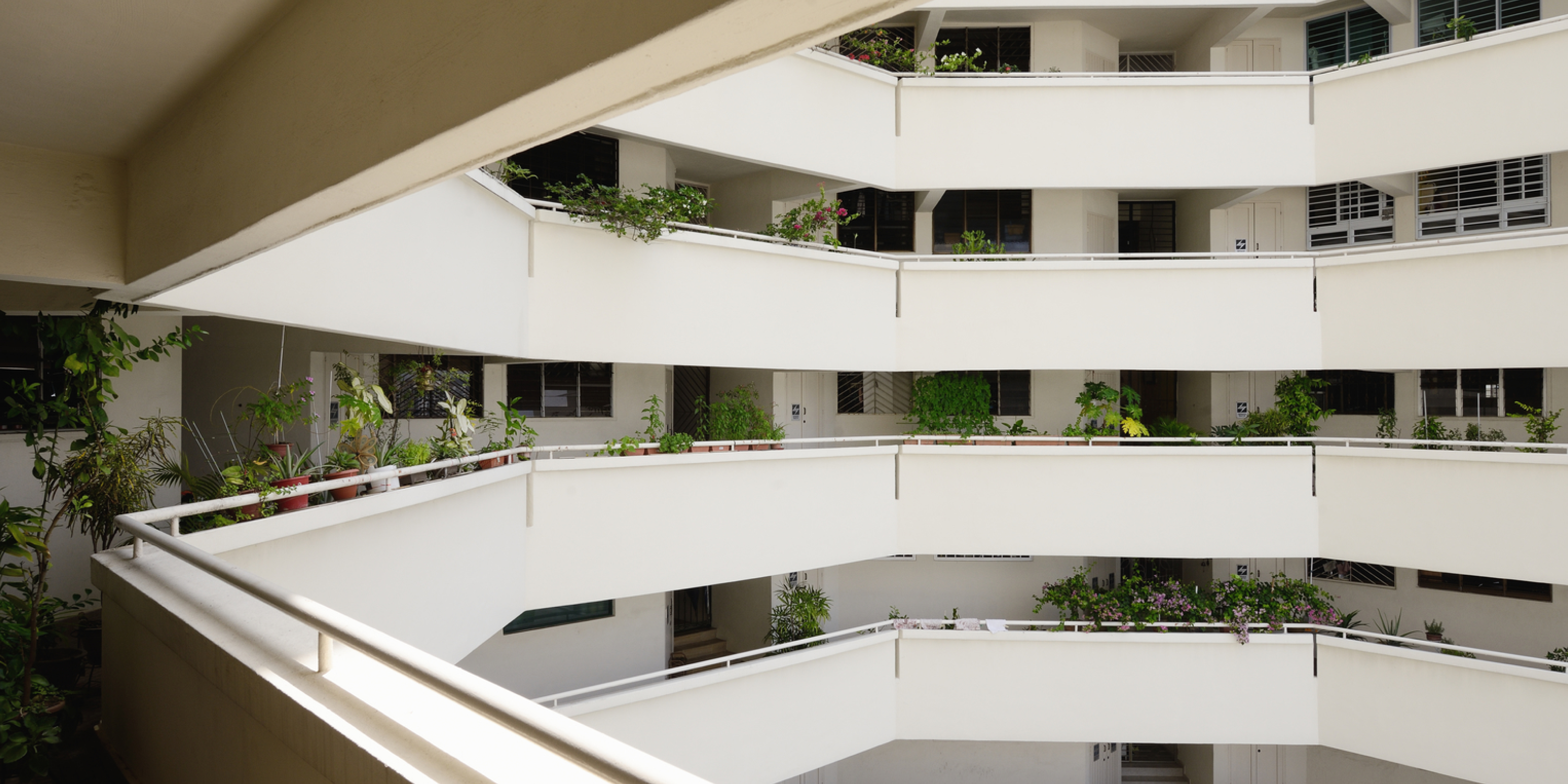 An image of an apartment building foyer where you can see green plants on the apartment balconies above