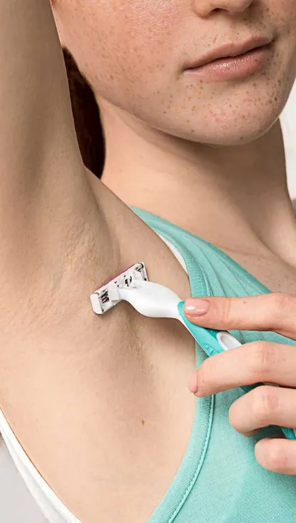 Mujer afeitándose la axila con la maquinilla de afeitar desechable Venus Simply 3 Sensitive