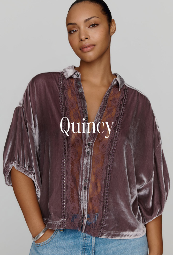 Woman wearing a mauve velvet button-up top with embroidered details and text reading Quincy on a gray background.