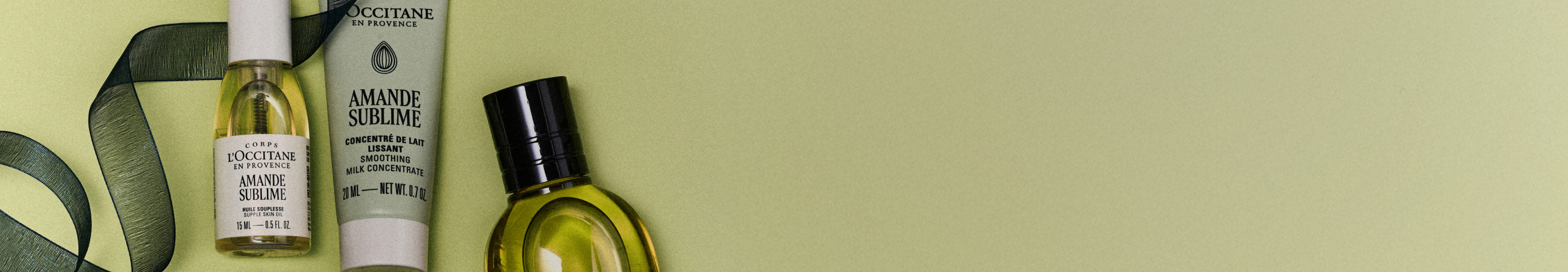L'Occitane Amande Sublime body care products arranged on a pale green background with decorative leaves.