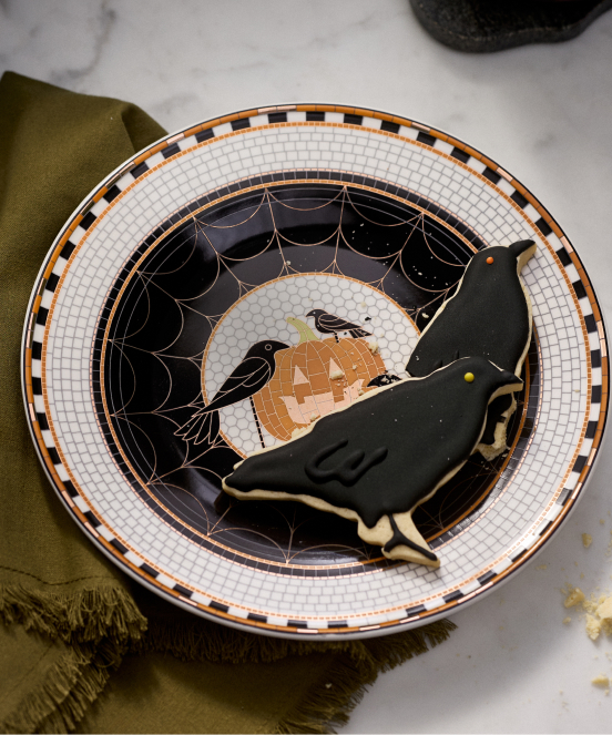 Halloween plate with black crow, pumpkin, and spider web design in black, orange, and white colors with checkered border.