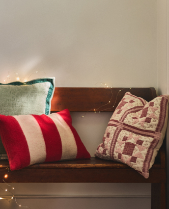Three decorative throw pillows on a brown leather sofa: red and white striped, teal textured, and burgundy patterned cushions.