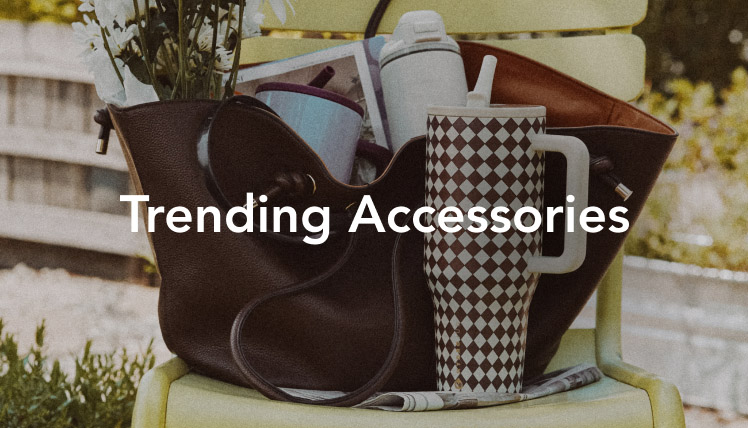 Black tote bag on yellow outdoor chair with checkered water bottle, sunglasses, and text reading Trending Accessories